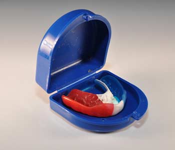 Red white and blue mouth guard and blue case on a white background